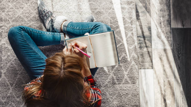 lady sitting down and writing something on a notebook