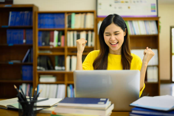 Excited happy student woman looking at laptop reading great news, passed exam, received university admission notification. 