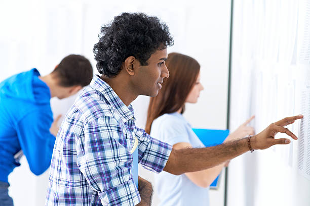 A young man student looking for his grades in the board