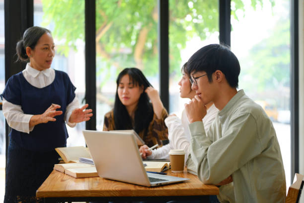 College students attentively listening to mature professor in the classroom stock photo