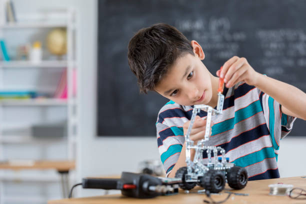 Handsome boy builds robot at school stock photo