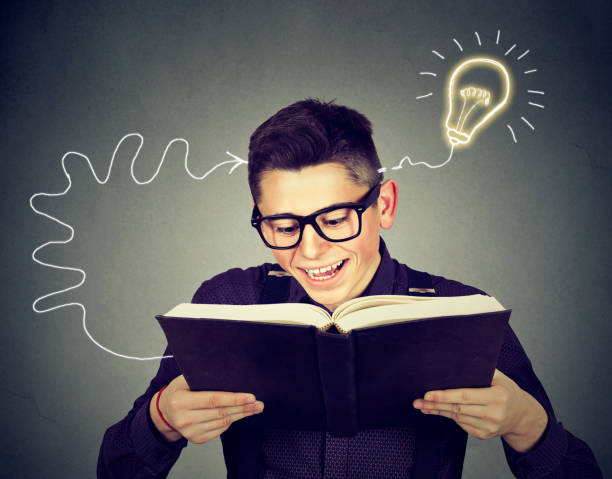 Amazed happy young man in glasses reading book 