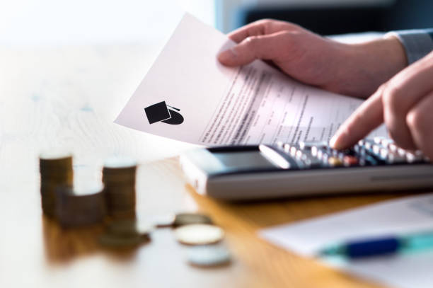 Man counting college savings fund, tuition fee or student loan with calculator. Education price and expenses concept. Money and papers on table. stock photo